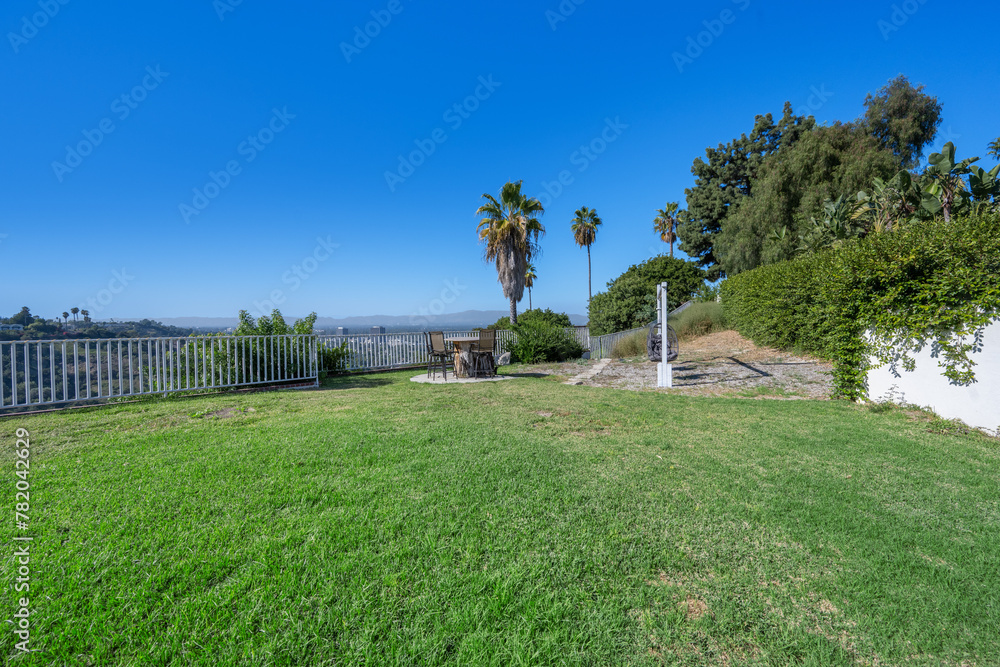 Spacious backyard with lush lawn, white fence, and two chairs in Hidden Hills, CA