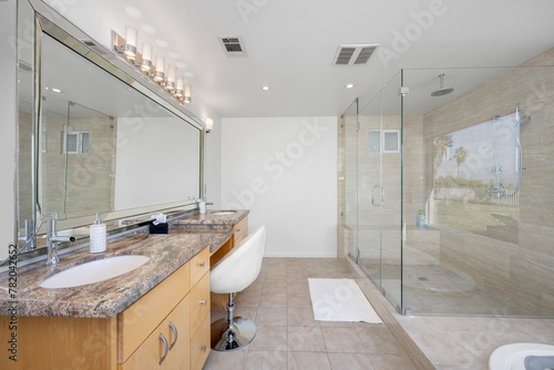 Spacious white bathroom with stone countertop, lit by sleek chrome fixtures
