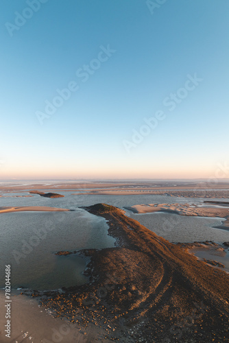 Drying shore at low tide of Plaat van Walsoorden at Ossenisse radar in the southern Netherlands under the brilliant orange-yellow glow of sunrise photo