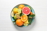 Different cut and whole citrus fruits on white wooden table, top view
