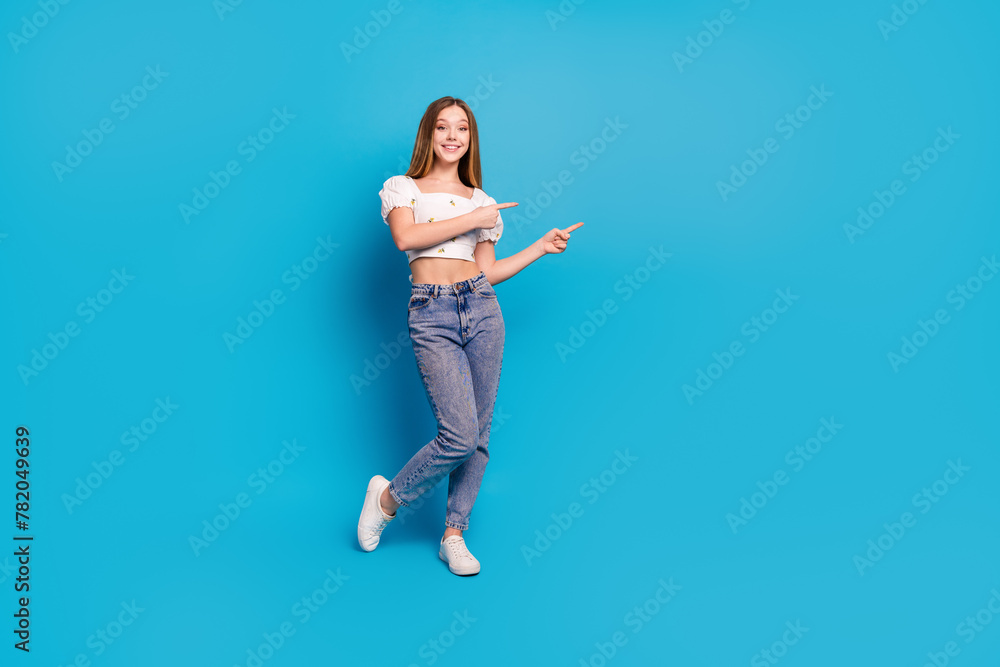 Full length portrait of lovely girl indicate fingers empty space wear top isolated on blue color background
