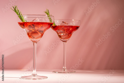 Refreshing cocktail with rosemary in a glass on a bright background. Summer party concept.
