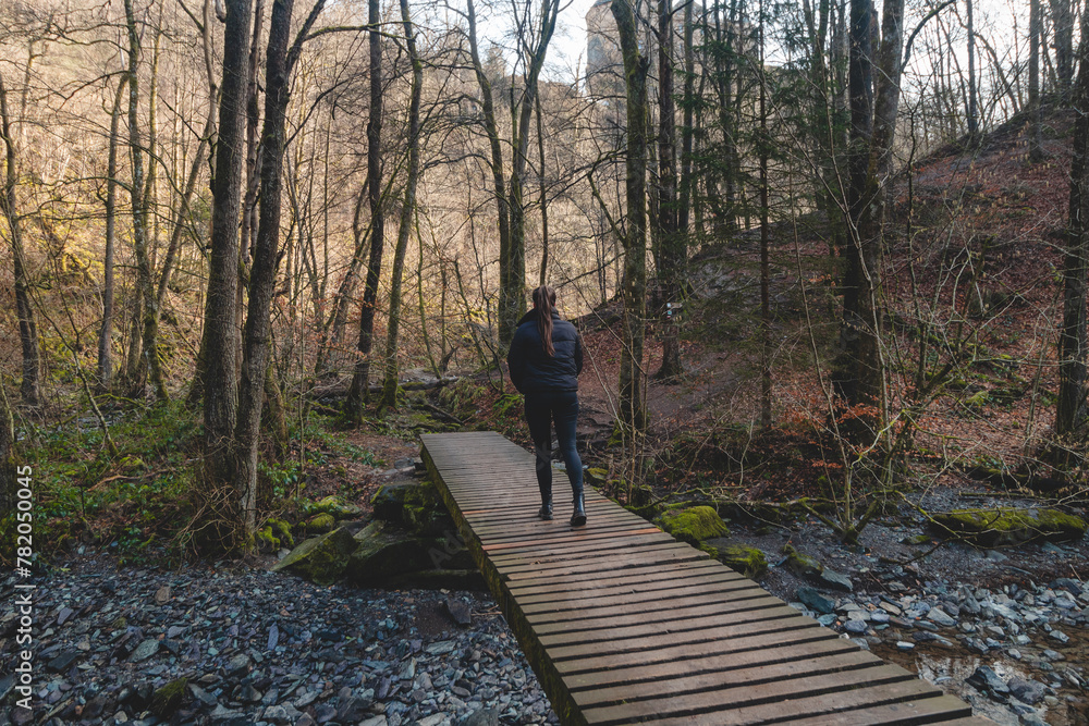 Woman walks along a wooden path in the Wallonia region of Belgium. Exploring the wilderness at Reinhardstein Castle in Belgium Woman walks along a wooden path in the Wallonia region of Belgium. Exploring the wilderness at Reinhardstein Castle in Belgium