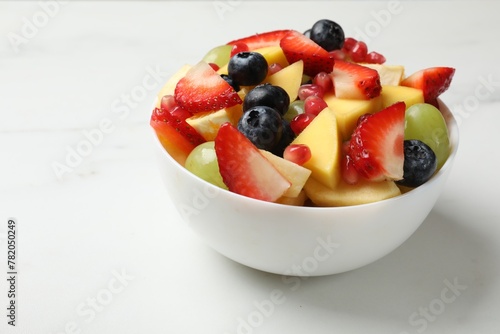 Tasty fruit salad in bowl on white table  closeup