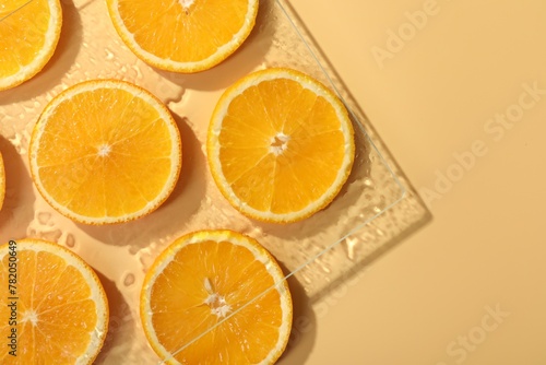 Slices of juicy orange and water on beige background, flat lay. Space for text
