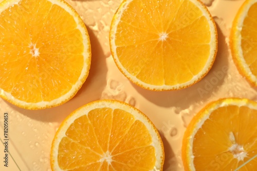 Slices of juicy orange and water on beige background  flat lay