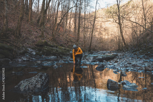 Traveler looks at a face of himself in a pond of water and visualizes his life old life. Self-visualization. Lost in thoughts. Discovering wildlife in Belgium