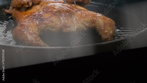 the chef flips a whole grilled chicken with a large fork