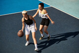 Two young women, friends, stand proudly on top of a basketball court, embodying strength and sportsmanship in the summer sun.