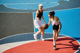 Two young women stand confidently on top of a basketball court, ready to take on the game with determination and skill.