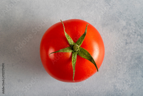 One red tomato on a light blue background, top view