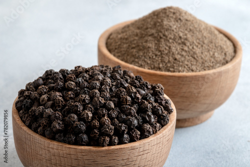 Ground black pepper with grains of black pepper on bright background

