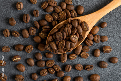 A spoon full of roasted coffee beans on black background,top view