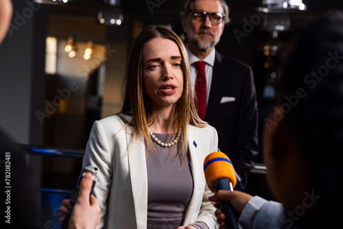 Political speech of EU consul during press campaign. Confident female European politician answers journalists questions, gives interview for media and television news in European Parliament building.