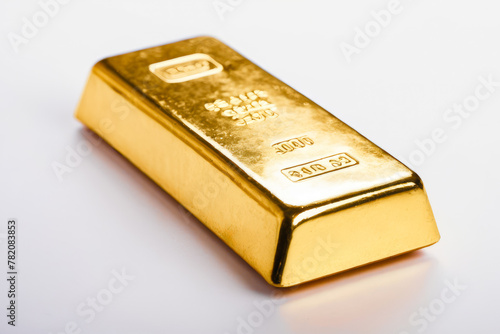 Gold bar rests on white backdrop. Engravings indicate weight, purity. Light reflects off surface, emphasizing value, quality