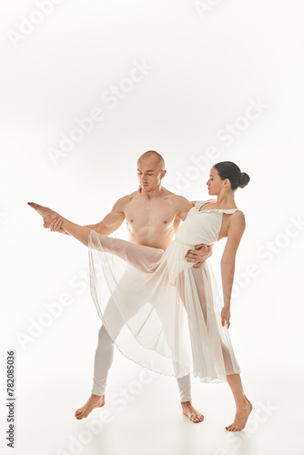 A shirtless young man and a woman in a white dress perform acrobatic dance moves in this studio shot on a white background.