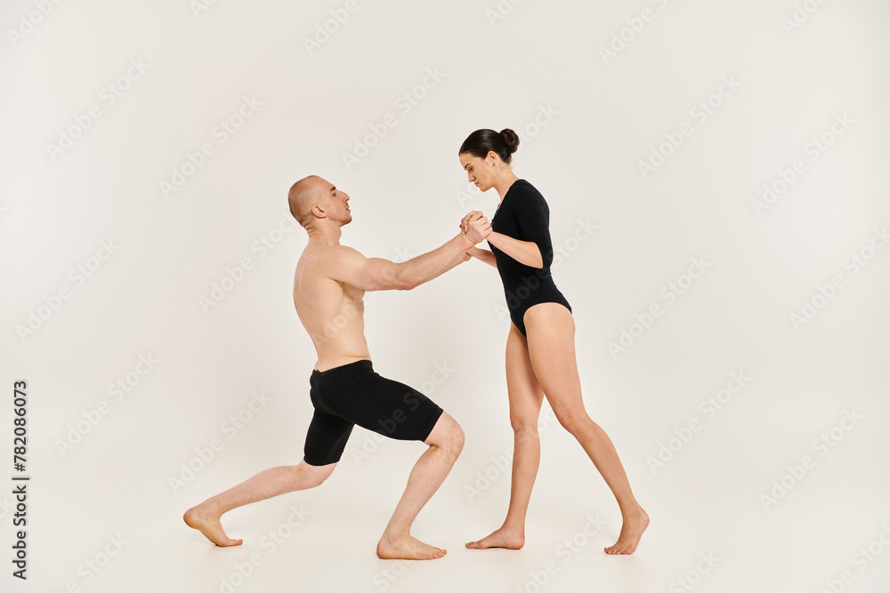 A shirtless young man and a woman performing intricate dance poses and acrobatic elements in a studio setting against a white background.