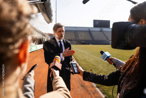 Interview of private investor at press conference for TV news in soccer stadium. Director of football team answering press questions and giving interview. Inspirational speech during press campaign.