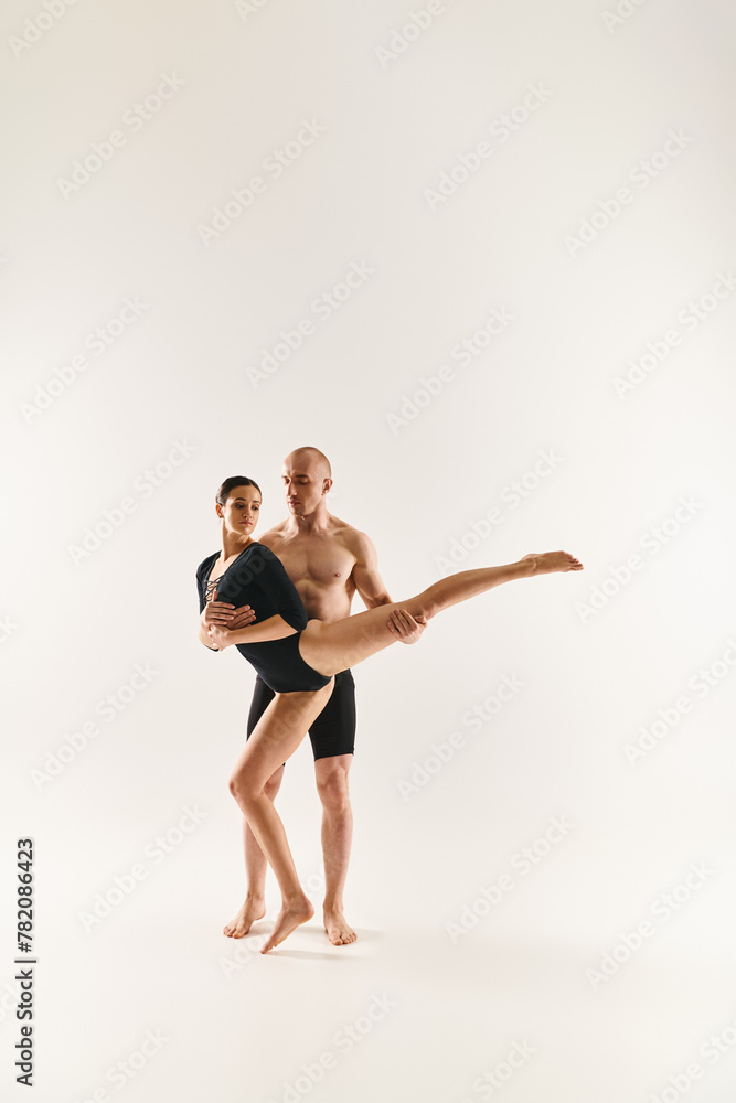 Young man shirtless and young woman dancing, performing acrobatic elements, in a couple, against a white background.