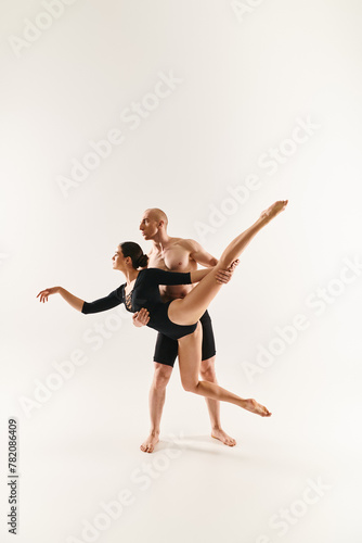 Shirtless young man and woman dance in mid-air, executing acrobatic moves in a studio setting against a white backdrop.