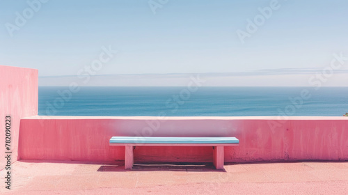 A wooden bench perched on top of a vibrant pink wall overlooking the ocean. The blue waters create a striking contrast against the pink background