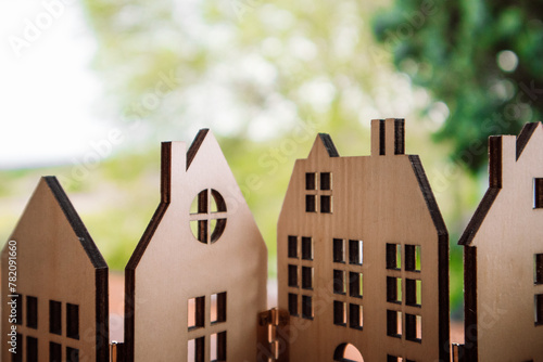 Wooden toy houses against natural green blurred background. A home in a forest, wood. Cardboard house window, roofs. Ecological rural buildings. photo
