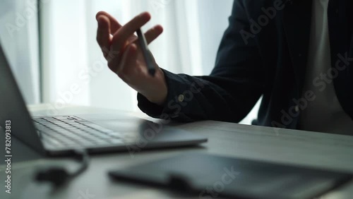 An office worker sits at a computer and holds a stylus from a graphics tablet. photo