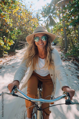 POV smiling young tanned woman riding a bicycle on the beach, summer vibes, casual, happy photo