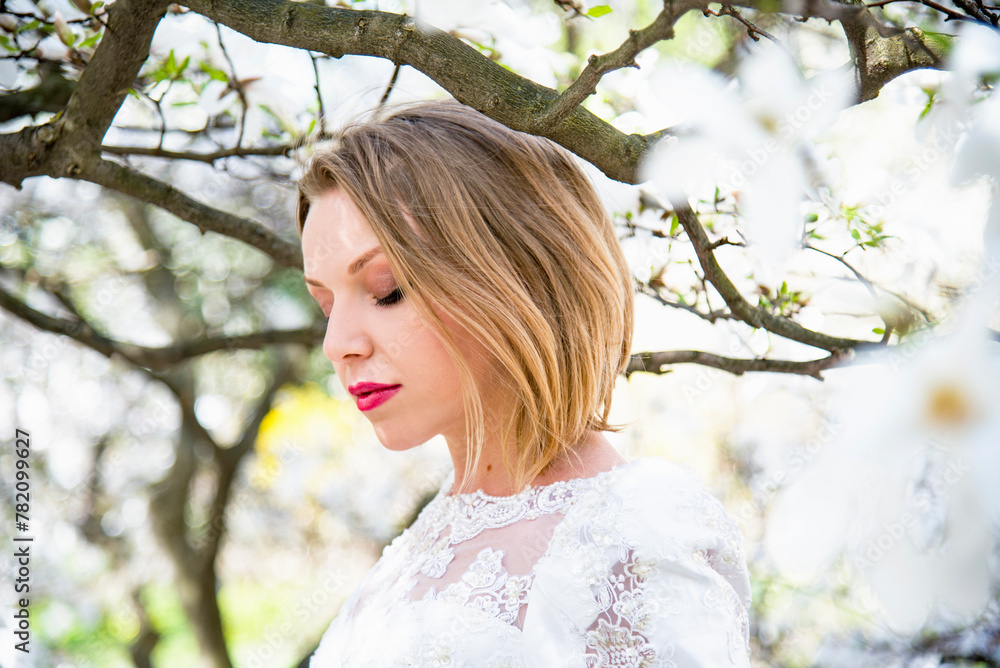 portrait of beautiful blonde smiling romantic bride in a white dress walking in blossoming magnolia garden on sunny spring day portrait of beautiful blonde smiling romantic bride in a white dress walking in blossoming magnolia garden on sunny spring day