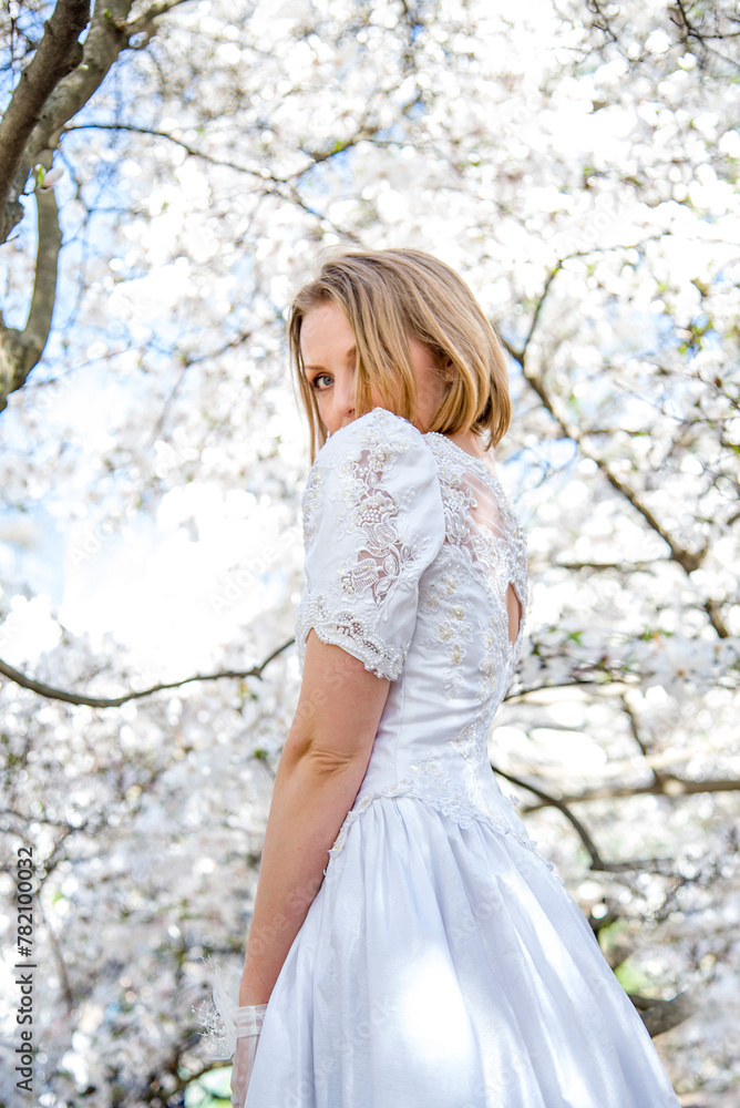 beautiful blonde smiling romantic bride in a white dress walking in blossoming magnolia garden on sunny spring day beautiful blonde smiling romantic bride in a white dress walking in blossoming magnolia garden on sunny spring day