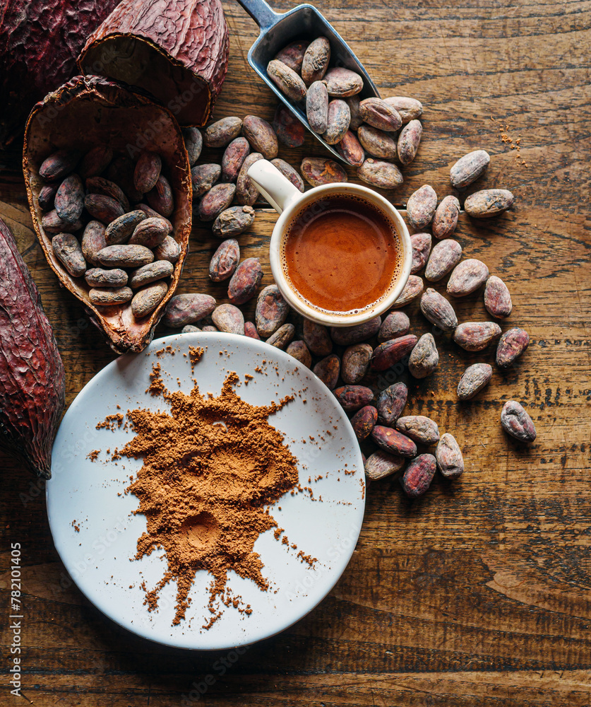 Top view of hot chocolate drink,cocoa drink and natural cocoa powder with brown cocoa beans and dry cacao pod  on a vintage wooden table. - obrazy, fototapety, plakaty 