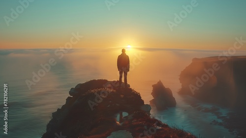 Man on cliff at sunset, admiring ocean view and colorful sky
