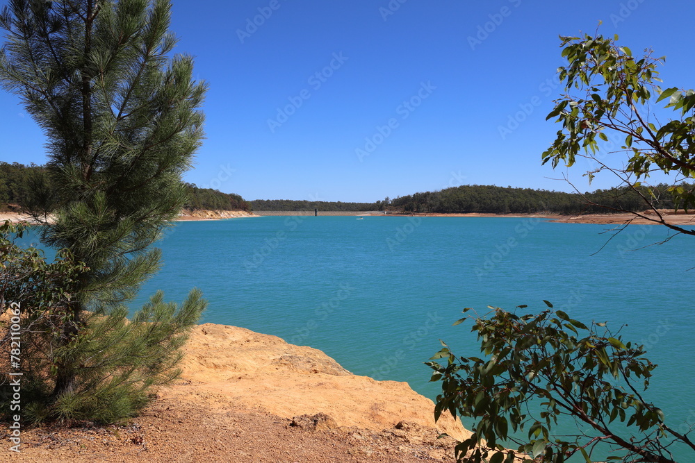 Logue Brook Dam (Lake Brockman) dam wall seen over turquoise colored water. Framed with trees.