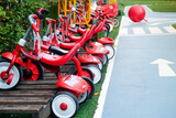 Red tricycles line up beside a track in a children's playground area