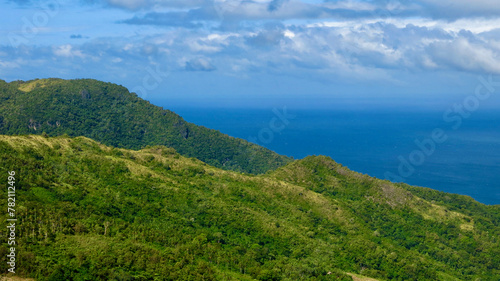 Aerial view of the mountain range of a tropical island. Mountains and hills of a tropical island covered with jungle against the backdrop of the blue sea.