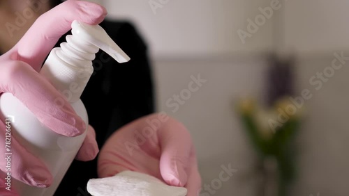 Wallpaper Mural a woman in pink gloves applies micellar water to a cotton pad. The cosmetologist is wearing a black shirt with long sleeves. Flowers are in the background. Torontodigital.ca