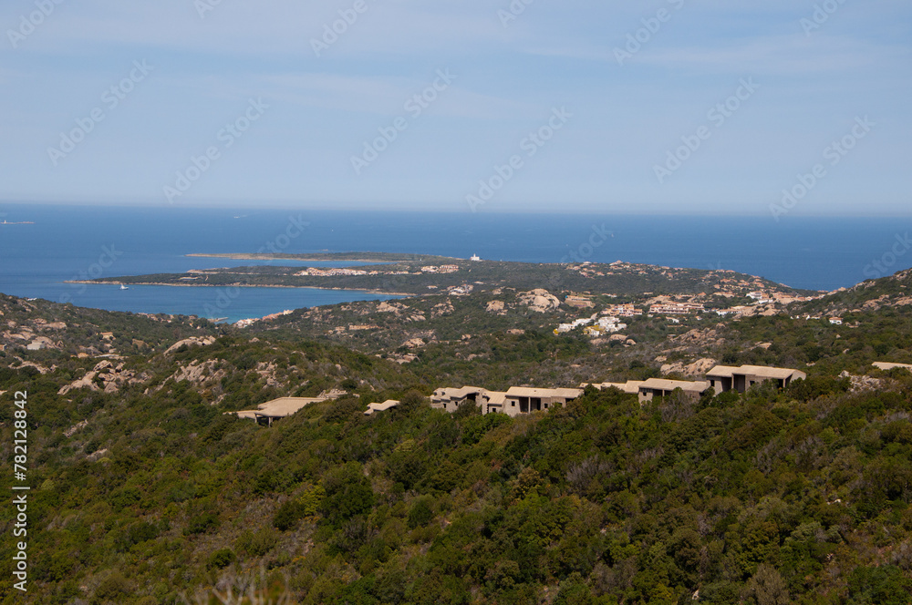 Serene landscape with a green shoreline and blue waters. Capo Ferro, Sardinia, Italy