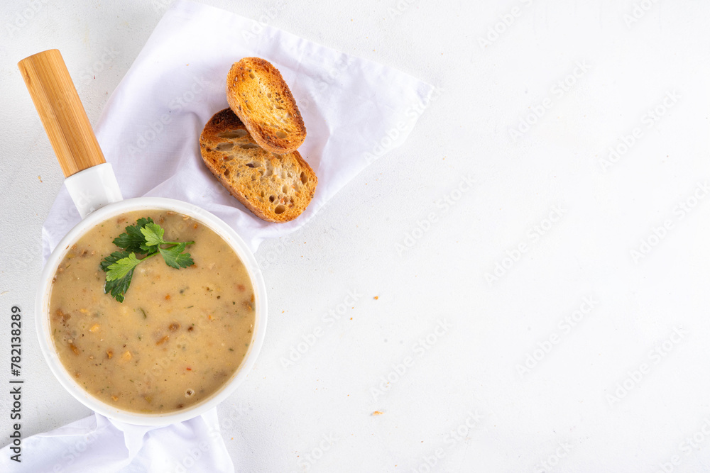 Thick vegan cream soup. Homemade golden yellow cream soup with herbs and croutons toast bread. Cheese, chicken, bean, corn cream soup in a plate on a white kitchen table copy space Thick vegan cream soup. Homemade golden yellow cream soup with herbs and croutons toast bread. Cheese, chicken, bean, corn cream soup in a plate on a white kitchen table copy space