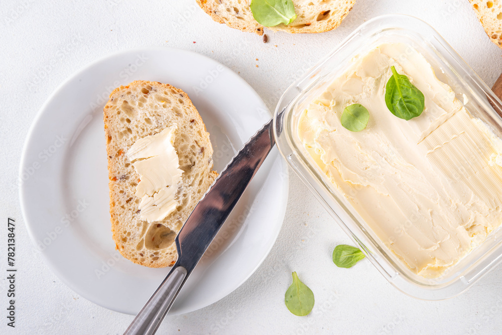 Homemade Vegan Butter, non-dairy creamy, plant based alternative butter with soy bean leave, and home baked bread on kitchen white table background Homemade Vegan Butter, non-dairy creamy, plant based alternative butter with soy bean leave, and home baked bread on kitchen white table background