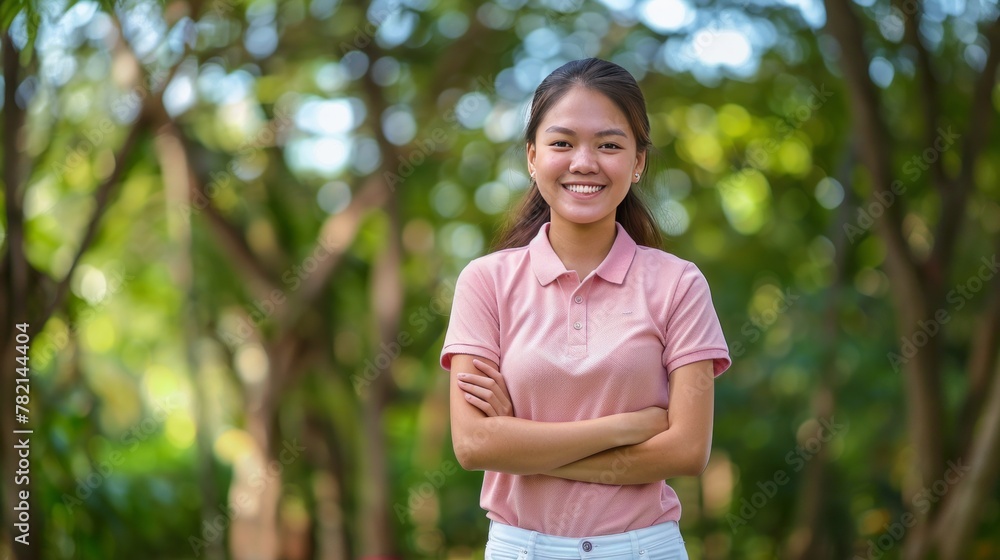 A young woman is smiling and standing in a park A young woman is smiling and standing in a park