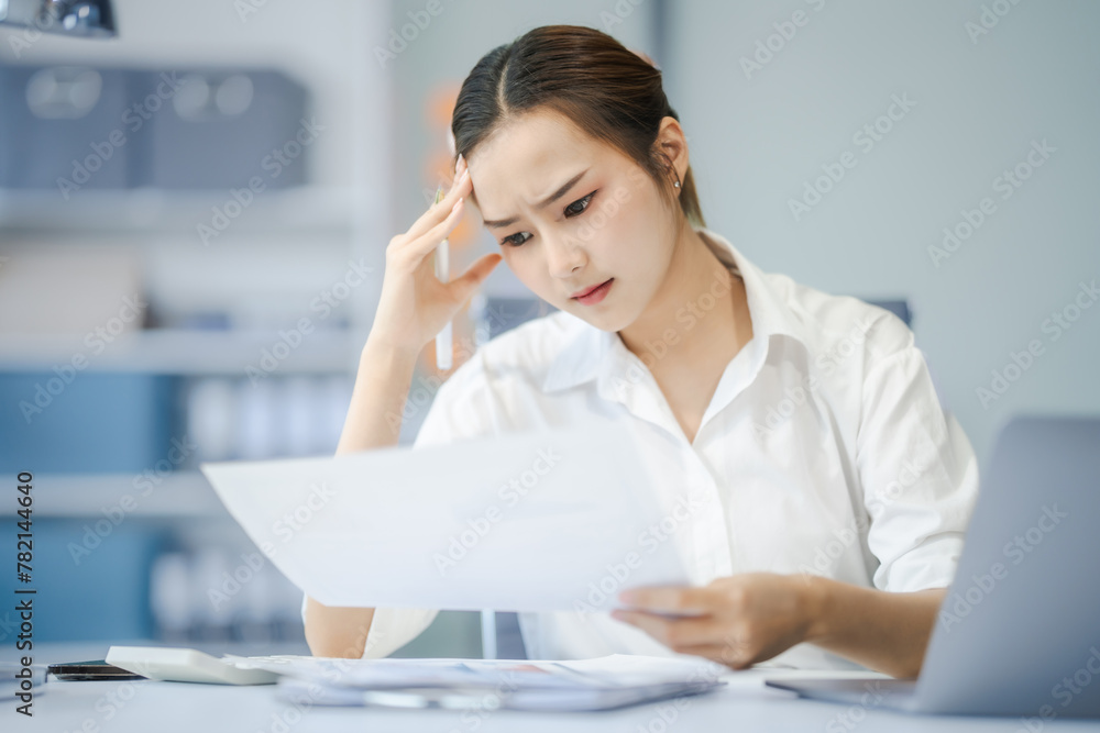 Asian people, In the corporate office, a young businesswoman sits at her desk, feeling exhausted and frustrated. facing financial crisis, overworked and stressed, hoping for a successful outcome. Asian people, In the corporate office, a young businesswoman sits at her desk, feeling exhausted and frustrated. facing financial crisis, overworked and stressed, hoping for a successful outcome.