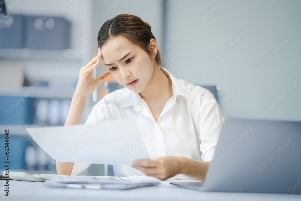 Asian people, In the corporate office, a young businesswoman sits at her desk, feeling exhausted and frustrated. facing financial crisis, overworked and stressed, hoping for a successful outcome. Asian people, In the corporate office, a young businesswoman sits at her desk, feeling exhausted and frustrated. facing financial crisis, overworked and stressed, hoping for a successful outcome.