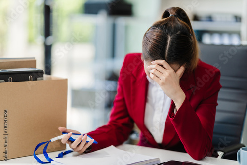 Fotografi In the office, an Asian woman carefully signs her resignation letter, feeling stressed