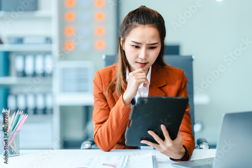 In Asian legal compliance, legal counseling office, a female lawyer reads a contract, advising on legal matters. clients, ensuring agreements align with laws and regulations, using tablet