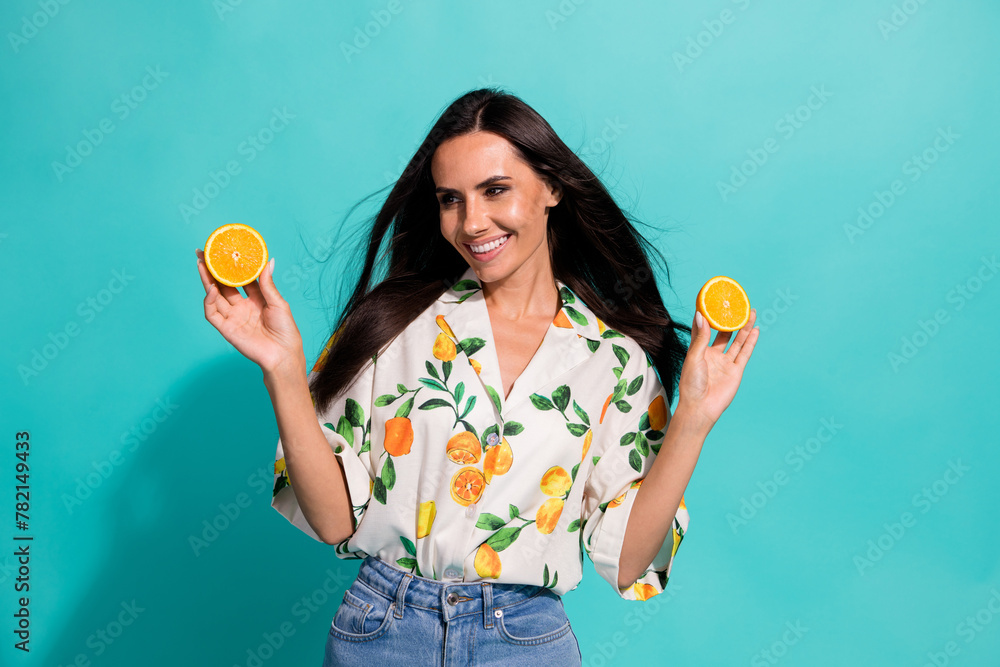 Photo of adorable gorgeous girl with long hair wear stylish shirt look empty space hold grapefruits isolated on teal color background Photo of adorable gorgeous girl with long hair wear stylish shirt look empty space hold grapefruits isolated on teal color background