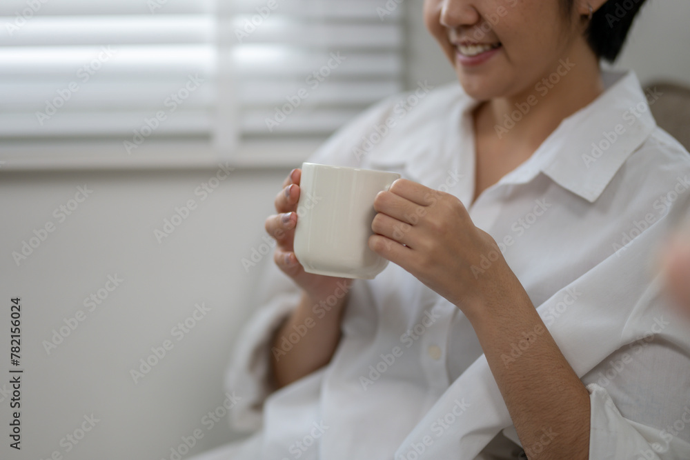 Close-up image capturing the contented smile of a woman savoring a warm drink from an oversized mug, in a cozy indoor setting. Close-up image capturing the contented smile of a woman savoring a warm drink from an oversized mug, in a cozy indoor setting.