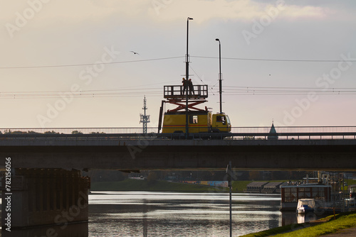 electricians are repairing lanterns on the bridge from the lift.
