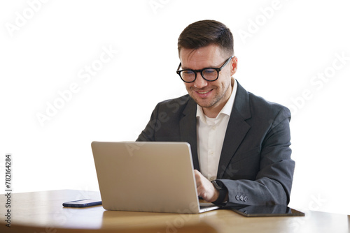 The manager is a positive man in a suit using a laptop.