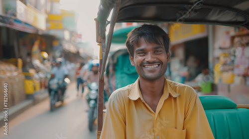 Indian rickshaw puller smiling, talking on the phone in a busy street photo