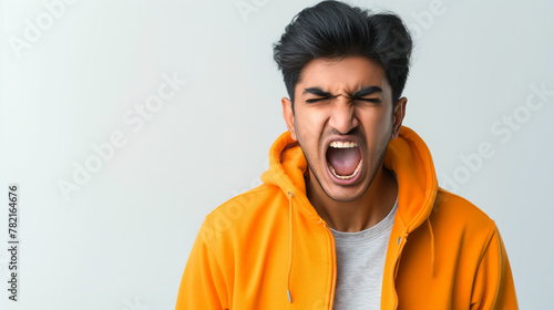 An Indian young man screaming out of frustrations against a light grey gradient background photo